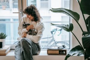 Woman holding her cat by a sunny window